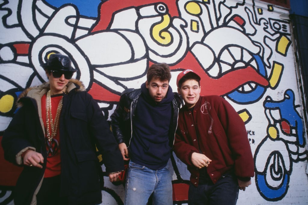 Portrait of members of American Rap group Beastie Boys as they pose in front of a mural (by Keith Haring), 1987. Pictured are, from left, Mike D (born Michael Diamond), MCA (born Adam Yauch, 1964 - 2012), and Ad-Rock (born Adam Horovitz). (Photo by Lynn Goldsmith/Corbis/VCG via Getty Images)