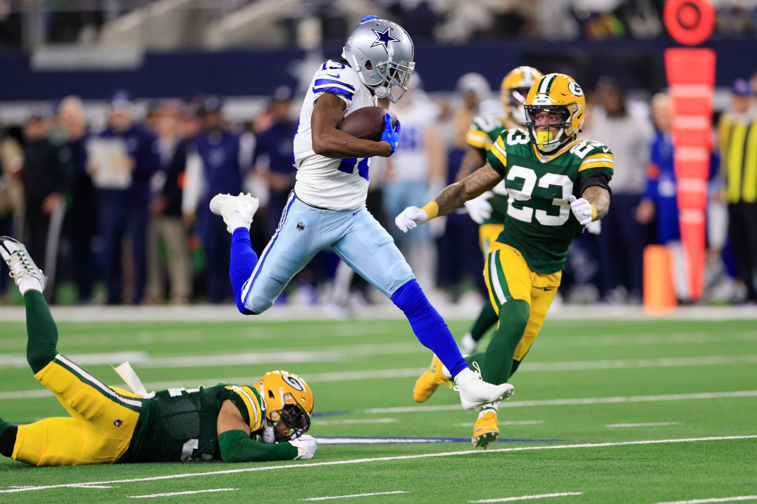 ARLINGTON, TEXAS - JANUARY 14: Michael Gallup #13 of the Dallas Cowboys is brought down by Jaire Alexander #23 of the Green Bay Packers during the third quarter of the NFC Wild Card Playoff game at AT&T Stadium on January 14, 2024 in Arlington, Texas. (Photo by Ron Jenkins/Getty Images)