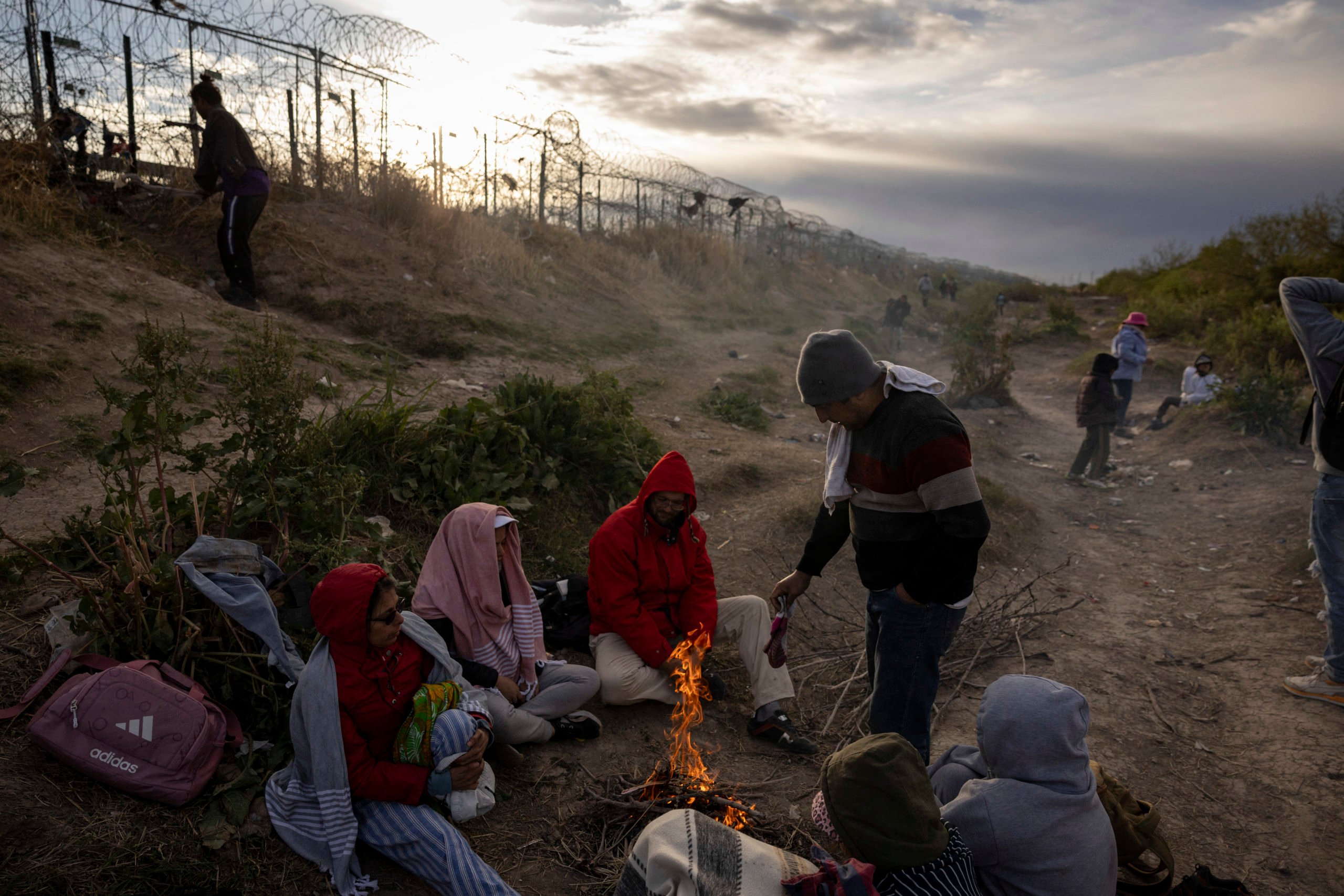EDITORS NOTE: Graphic content / Migrants from Venezuela sit by a makeshift fire to warm up as they wait to enter and seek asylum in El Paso, Texas from Ciudad Juarez, Chihuahua, Mexico on April 2, 2024. An appeals court is scheduled to hear arguments on the constitutionality of Senate Bill 4 that would allow state law enforcement officials to detain and arrest undocumented immigrants suspected of illegally crossing into the United States. (Photo by CHRISTIAN MONTERROSA/AFP via Getty Images)