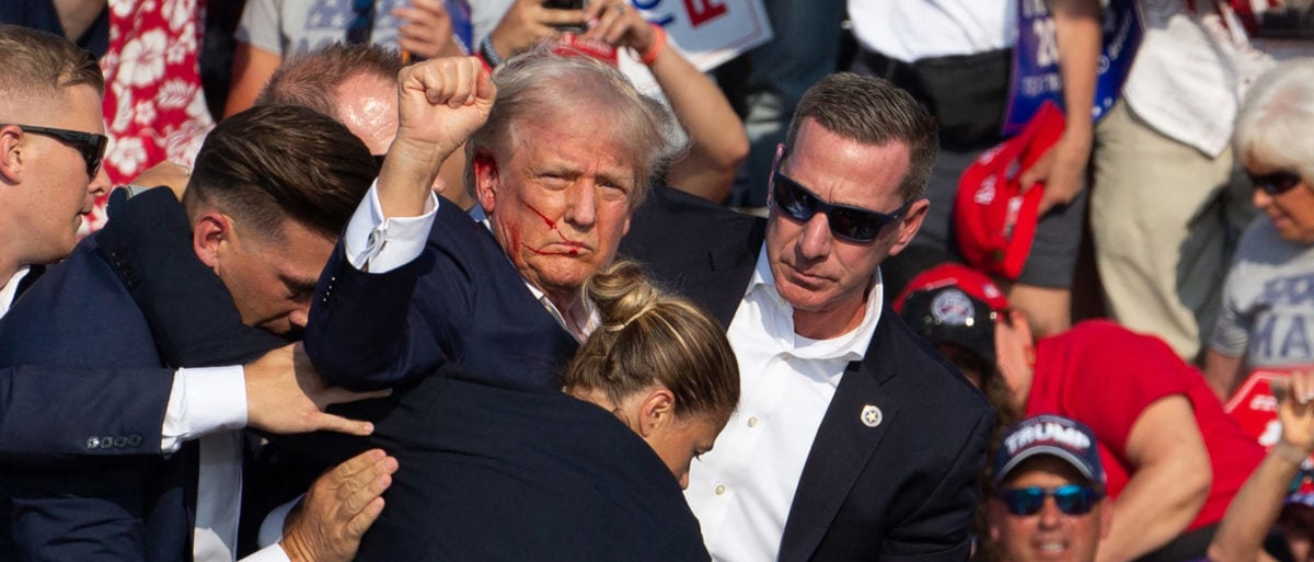 TOPSHOT - Republican candidate Donald Trump is seen with blood on his face surrounded by secret service agents (Photo by Rebecca DROKE / AFP) (Photo by REBECCA DROKE/AFP via Getty Images)