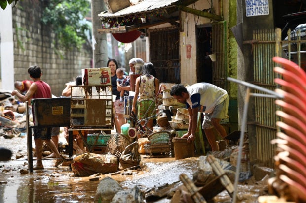 Residents check their belongings at a village in Manila on July 25, 2024, a day after heavy rains fuelled by Typhoon Gaemi and the seasonal monsoon lashed Manila and surrounding regions in recent days. (Photo by TED ALJIBE/AFP via Getty Images)