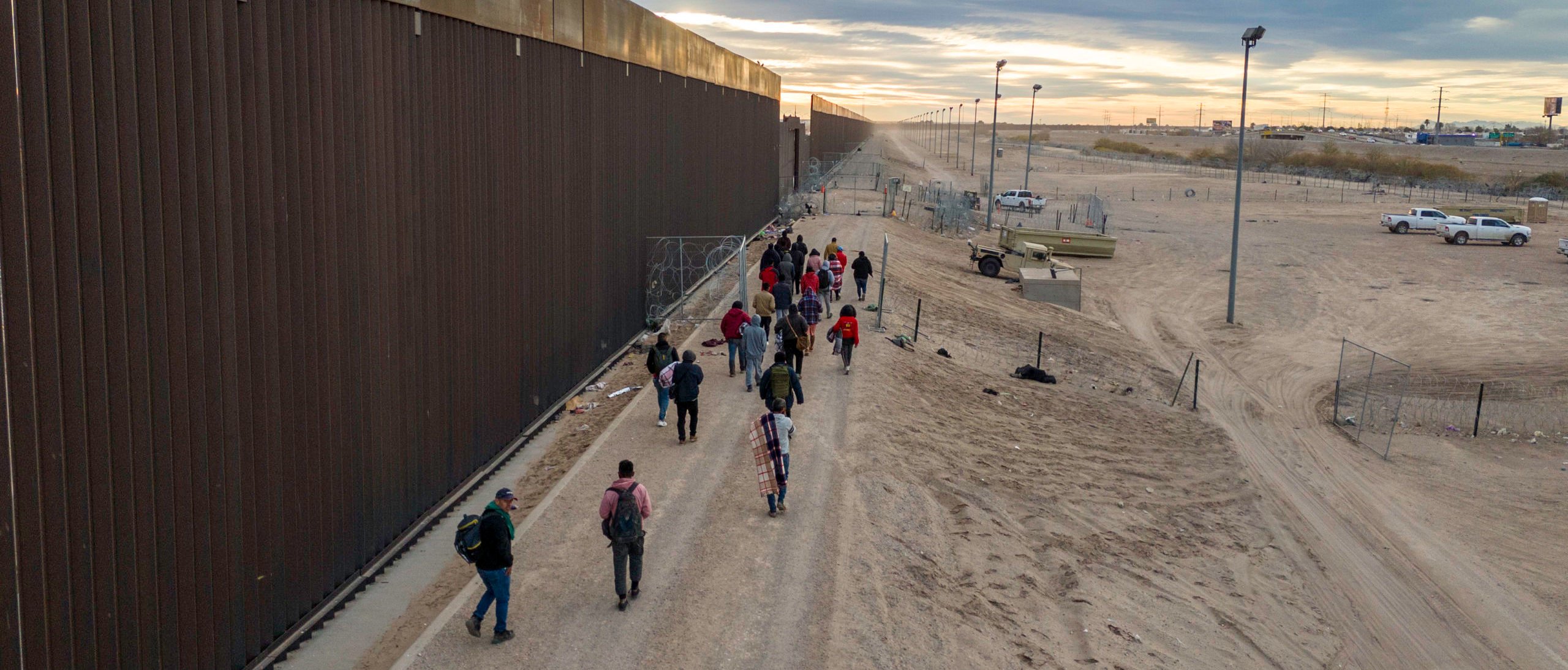 EL PASO, TEXAS - FEBRUARY 01: Seen from an aerial view, immigrants walk along the U.S.-Mexico border wall after crossing the Rio Grande into El Paso, Texas on February 01, 2024 from El Paso, Texas. They had also passed through razor wire set by Texas National Guard troops in order to proceed for processing by U.S. Border Patrol agents. (Photo by John Moore/Getty Images)