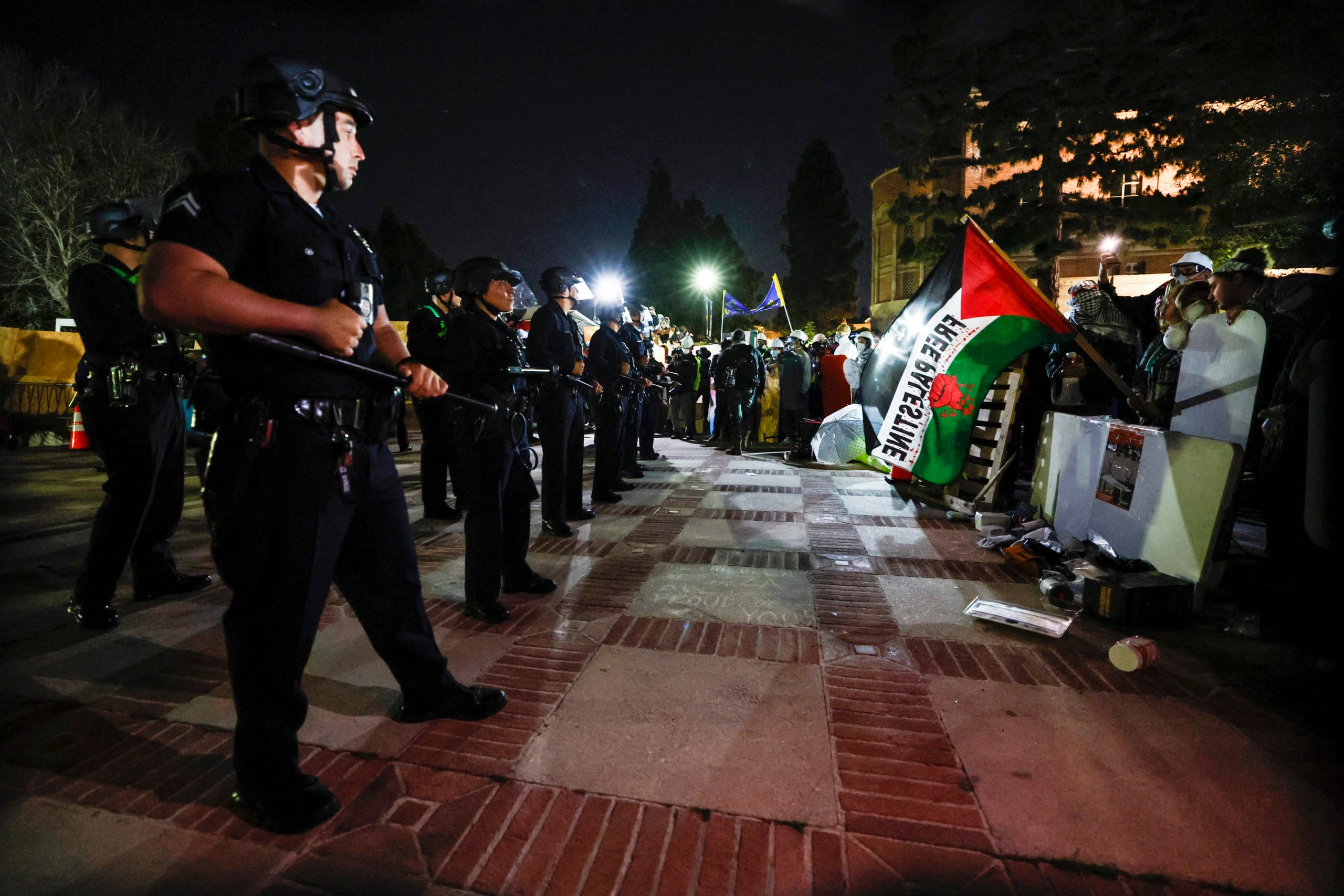 TOPSHOT - Pro-Palestinian students stand their ground after police breached their encampment the campus of the University of California, Los Angeles (UCLA) in Los Angeles, California, early on May 2, 2024. Police deployed a heavy presence on US university campuses on May 1 after forcibly clearing away some weeks-long protests against Israel's war with Hamas. Dozens of police cars patrolled at the University of California, Los Angeles campus in response to violent clashes overnight when counter-protesters attacked an encampment of pro-Palestinian students. (Photo by ETIENNE LAURENT/AFP via Getty Images)