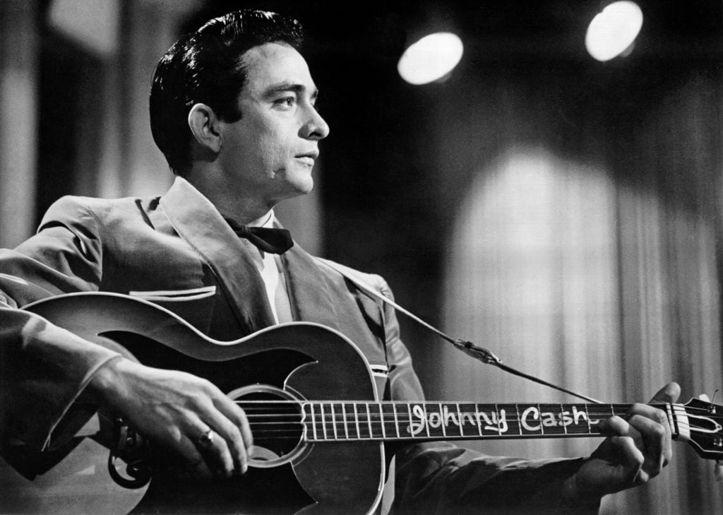 1957: Country singer/songwriter Johnny Cash performs onstage with an acoustic guitar in Sun Records publicity shot in 1957. (Photo by Michael Ochs Archives/Getty Images)