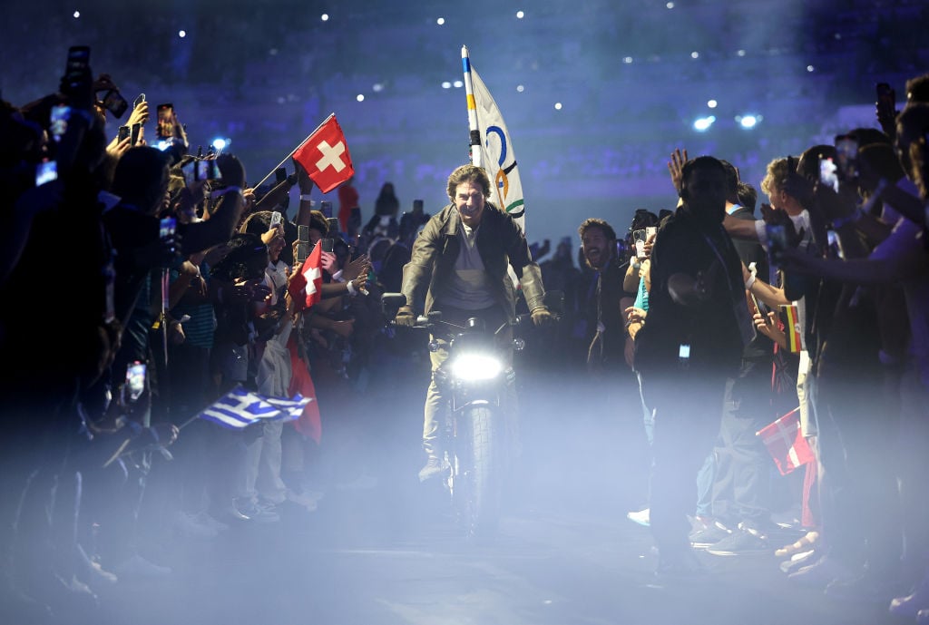 PARIS, FRANCE - AUGUST 11: American Actor and Film Producer Tom Cruise rides on a Motorbike with the IOC Flag during the Closing Ceremony of the Olympic Games Paris 2024 at Stade de France on August 11, 2024 in Paris, France. (Photo by Jamie Squire/Getty Images)