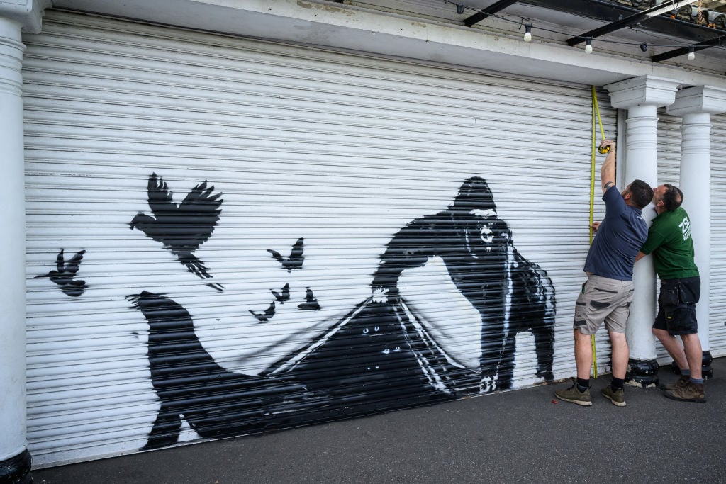 LONDON, ENGLAND - AUGUST 13: London Zoo staff members measure up a new mural by street artist Banksy of a gorilla freeing animals on the shutters at London Zoo on August 13, 2024 in London, England. The mural has been claimed by Banksy in an Instagram post, who has also painted eight animal-themed artworks in the London area over the preceding eight days. (Photo by Leon Neal/Getty Images)